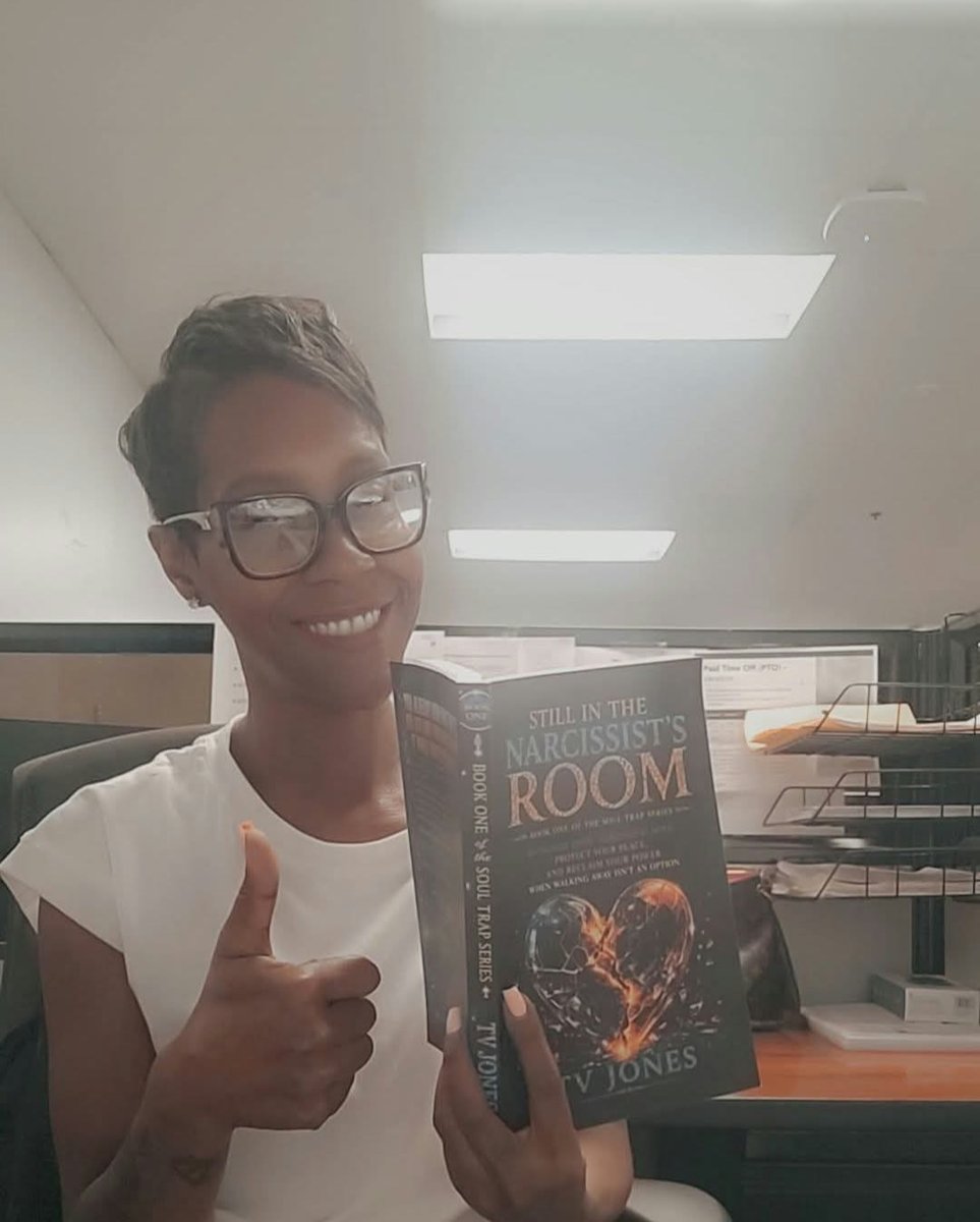 A smiling reader in glasses giving a thumbs-up while holding Still In The Narcissist’s Room
